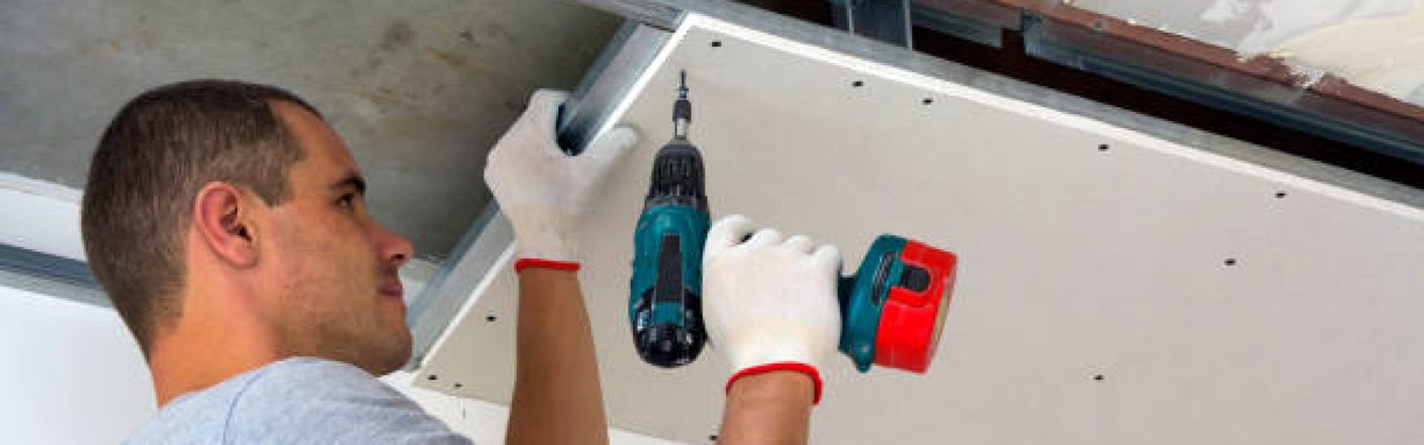istockphoto-1155293469-612×612 Construction worker assemble a suspended ceiling with drywall and fixing the drywall to the ceiling metal frame with screwdriver.